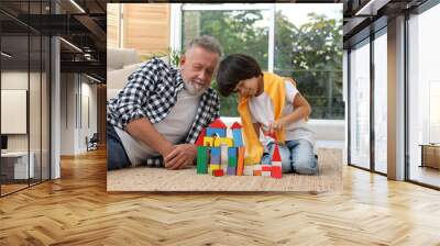 Happy grandfather and his grandson playing with toy building blocks together at home Wall mural