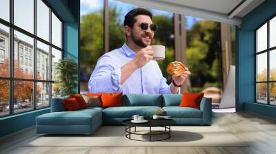 Happy man having breakfast in outdoor cafe Wall mural