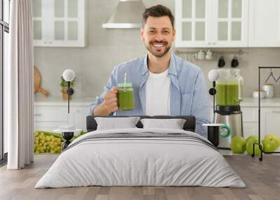 Happy man holding glass of delicious smoothie at white marble table in kitchen Wall mural