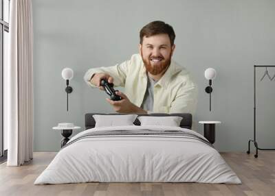 Happy man playing video game with controller on grey background Wall mural