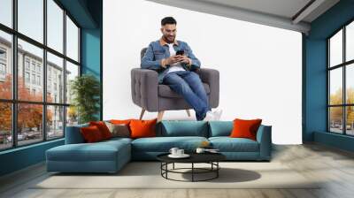 Happy man using smartphone in armchair on white background, space for text Wall mural