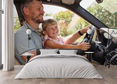 Happy man with his daughter holding steering wheel inside car Wall mural