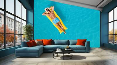 Happy man with inflatable mattress in swimming pool, top view and space for text. Summer vacation Wall mural