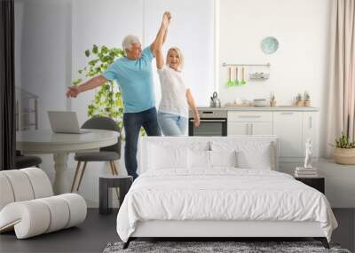 Happy mature couple dancing together in kitchen Wall mural