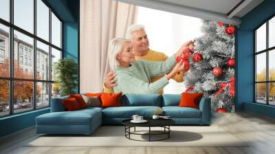 Happy mature couple decorating Christmas tree at home Wall mural