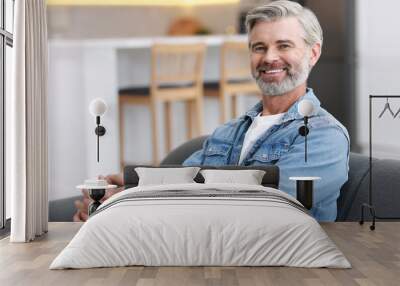 Happy middle aged man on sofa indoors Wall mural