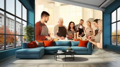 Happy people cooking food together in kitchen Wall mural