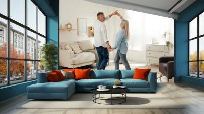 Happy senior couple dancing together in living room Wall mural