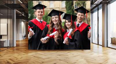 Happy students with diplomas after graduation ceremony outdoors Wall mural