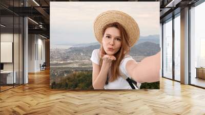 Happy woman in straw hat taking selfie in mountains Wall mural