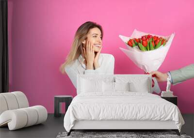 Happy woman receiving red tulip bouquet from man on pink background. 8th of March celebration Wall mural