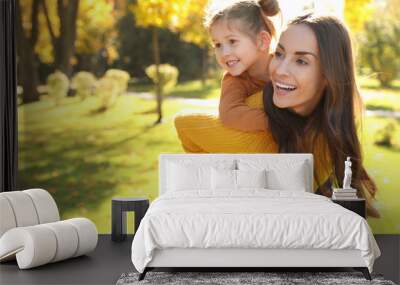 Happy woman with little daughter in sunny park. Autumn walk Wall mural