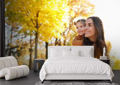 Happy woman with little daughter in sunny park. Autumn walk Wall mural