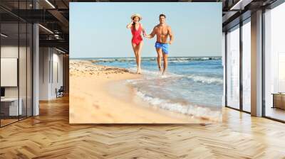 Happy young couple having fun at beach on sunny day Wall mural