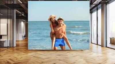 Happy young couple having fun at beach on sunny day Wall mural