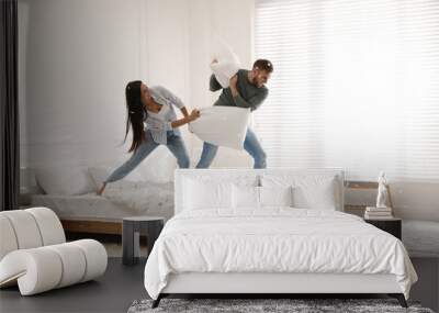 Happy young couple having fun pillow fight in bedroom Wall mural