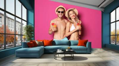 Happy young couple in beachwear with cocktails on color background Wall mural