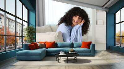 Happy young woman in stylish light blue sweater indoors Wall mural