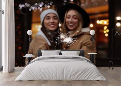 Happy young women with sparklers at winter fair Wall mural