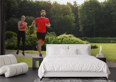 Healthy lifestyle. Happy couple running outdoors on sunny day, space for text Wall mural