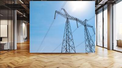 High voltage tower with electricity transmission power lines against blue sky, low angle view Wall mural