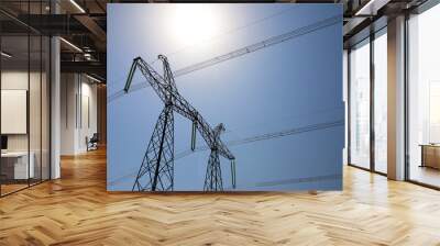 High voltage tower with electricity transmission power lines against blue sky, low angle view Wall mural