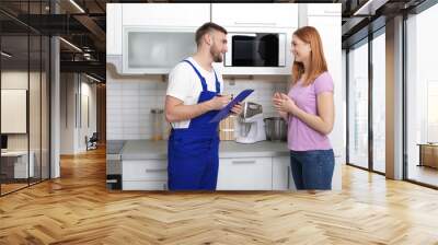 Housewife and repairman near microwave oven in kitchen Wall mural