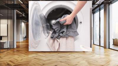 Housewife putting clothes into washing machine Wall mural