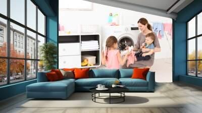 Housewife with little children doing laundry at home Wall mural