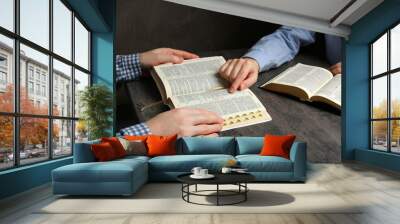 Humble couple reading Bibles at grey table together, closeup Wall mural