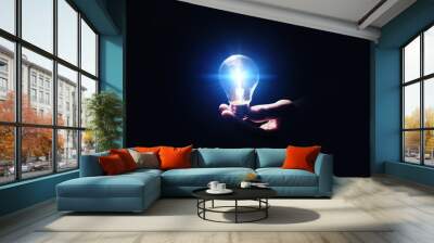 Idea concept. Man with glowing light bulb in darkness, closeup Wall mural