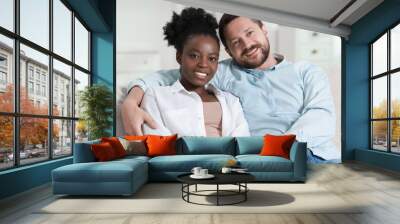 International relationships. Portrait of lovely couple on sofa at home Wall mural