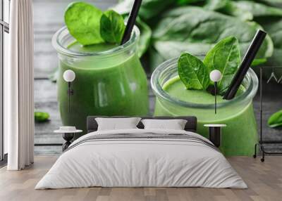 jars of healthy green smoothie with fresh spinach on grey wooden table, closeup Wall mural