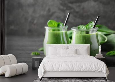 Jars of healthy green smoothie with fresh spinach on grey wooden table. Space for text Wall mural