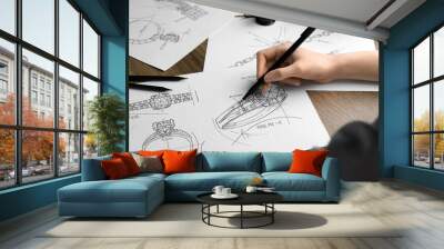 Jeweler drawing sketch of elegant ring on paper at wooden table, closeup Wall mural