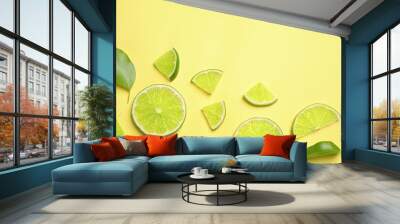 Juicy fresh lime slices and green leaves on yellow background, flat lay. Space for text Wall mural