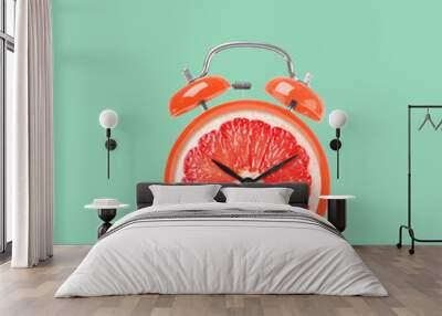 Juicy grapefruit on alarm clock dial against turquoise background. Creative poster Wall mural