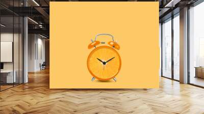 Juicy orange on alarm clock dial against light orange background. Creative poster Wall mural