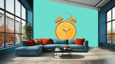 Juicy orange on alarm clock dial against turquoise background. Creative poster Wall mural