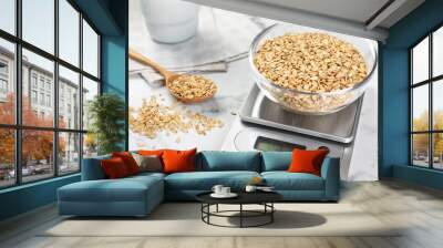 Kitchen scale with bowl of dry oats and spoon on white marble table, closeup Wall mural