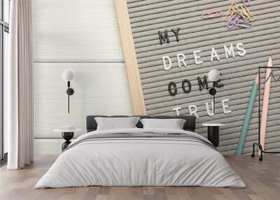 Letter board with phrase My Dreams Come True, pencils and paper clips on white wooden table, top view Wall mural