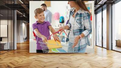 Little boy choosing school supplies with mother in stationery shop Wall mural