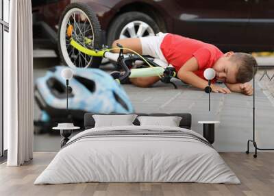 Little boy fallen from bicycle after car accident and helmet on road Wall mural