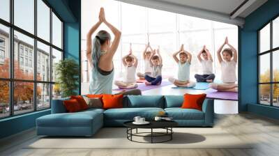 Little children and their teacher practicing yoga in gym Wall mural