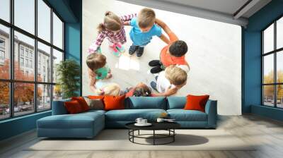 Little children making circle with hands around each other indoors, top view. Unity concept Wall mural