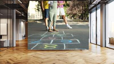 Little children playing hopscotch drawn with chalk on asphalt outdoors Wall mural