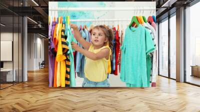 Little girl choosing clothes on rack indoors Wall mural