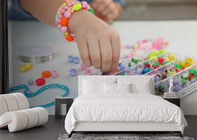 Little girl making beaded jewelry at table, closeup Wall mural