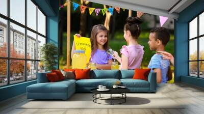 Little girl selling natural lemonade to kids in park. Summer refreshing drink Wall mural