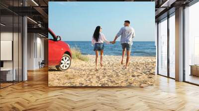 Lovely couple running on sandy beach. Summer trip Wall mural